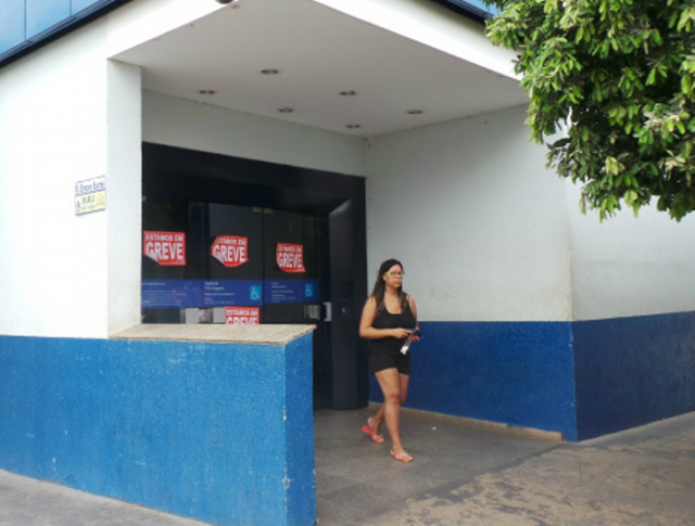 Cliente deixa agência da Caixa Econômica Federal na rua Paranaíba, no centro de Três Lagoas, após sacar dinheiro no caixa eletrônico; na porta, adesivos indicativos de greve (Foto: Ricardo Ojeda)